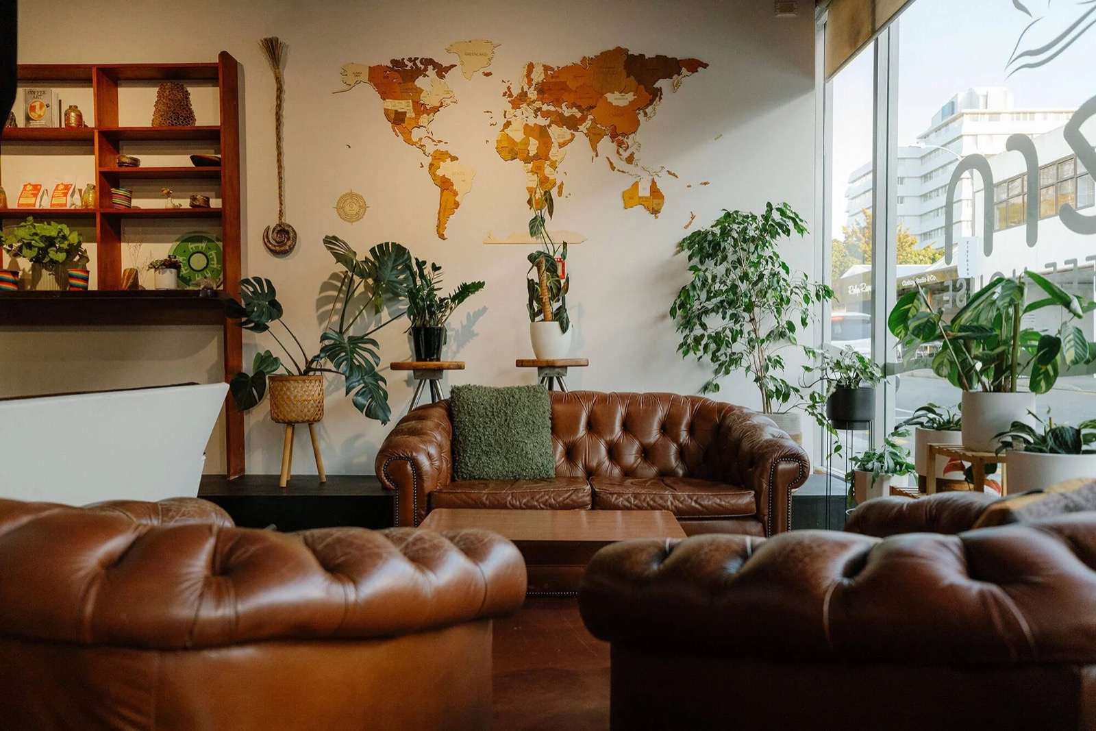 Tern's lounge: leather sofas, a wooden world map on the wall and plants by the window